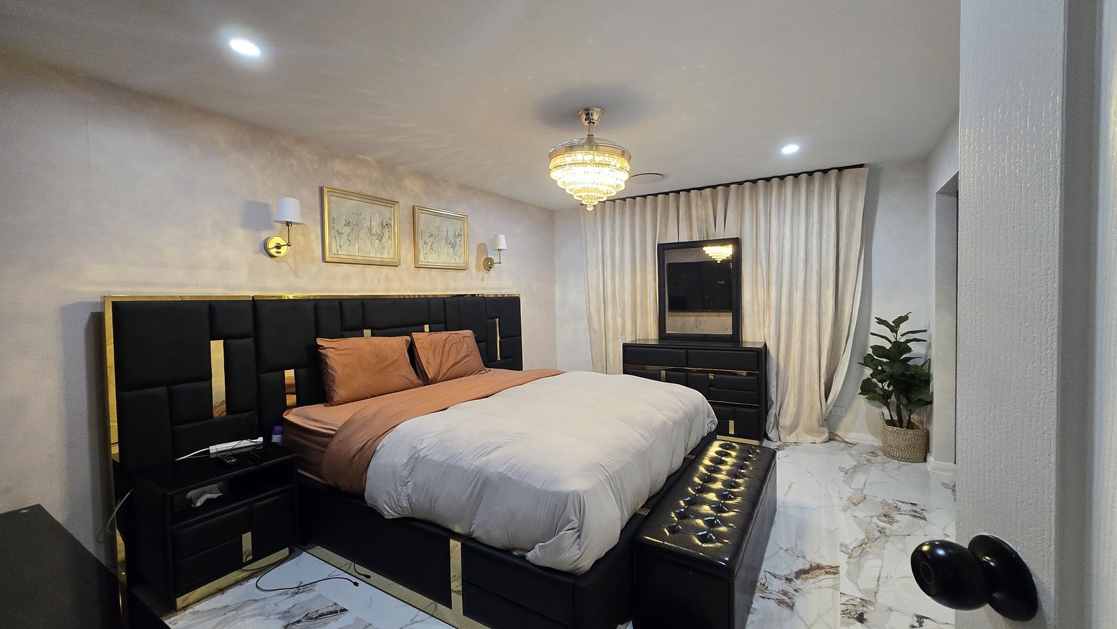 Textured wallpaper, brass sconce and botanical art in gold frames above the headboard