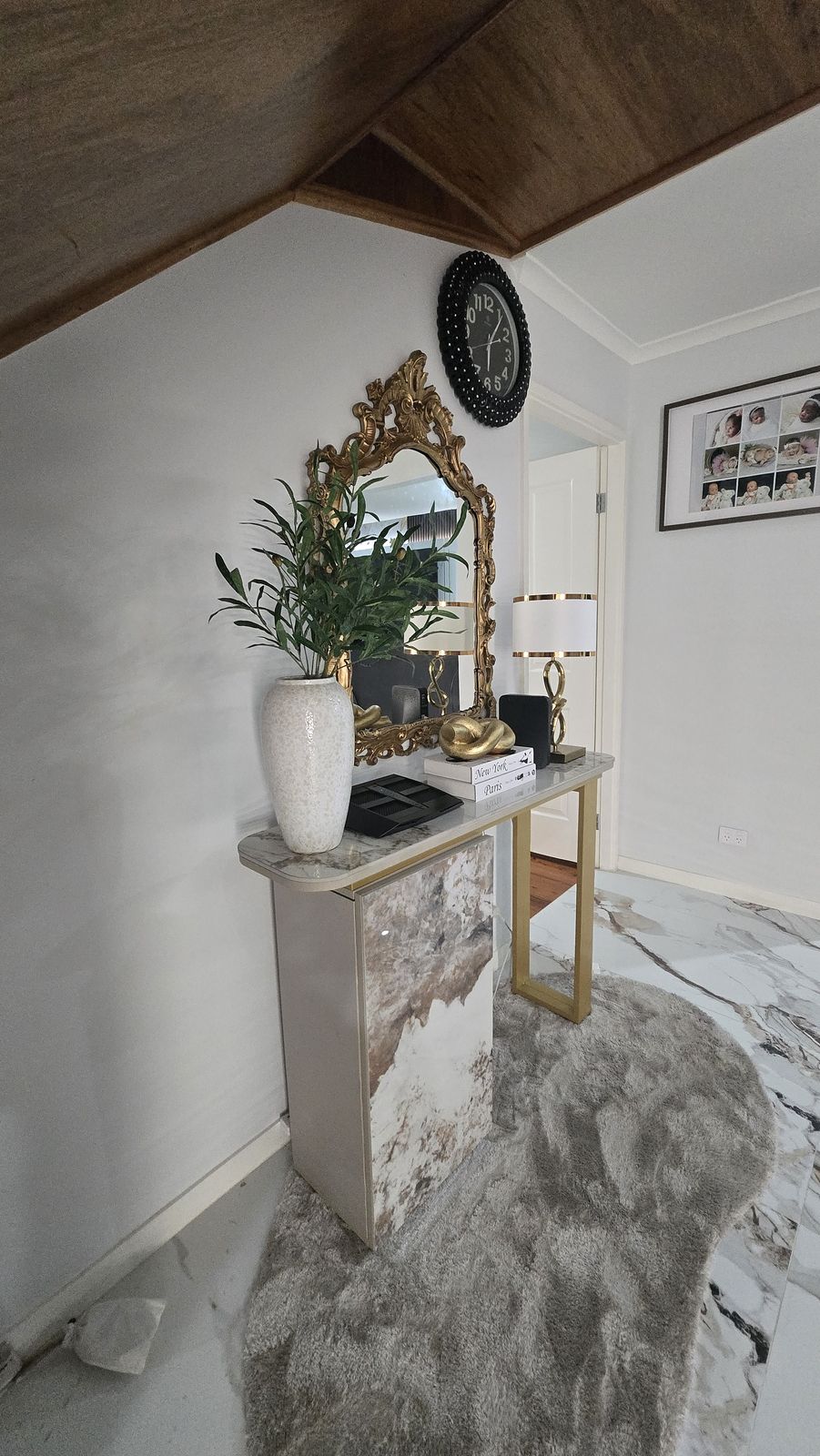 The entry on reveal night — gilded mirror, marble console and timber ceiling detail