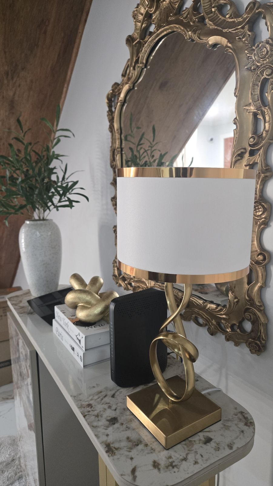 Gilded baroque mirror with sculptural gold lamp — material and light in dialogue