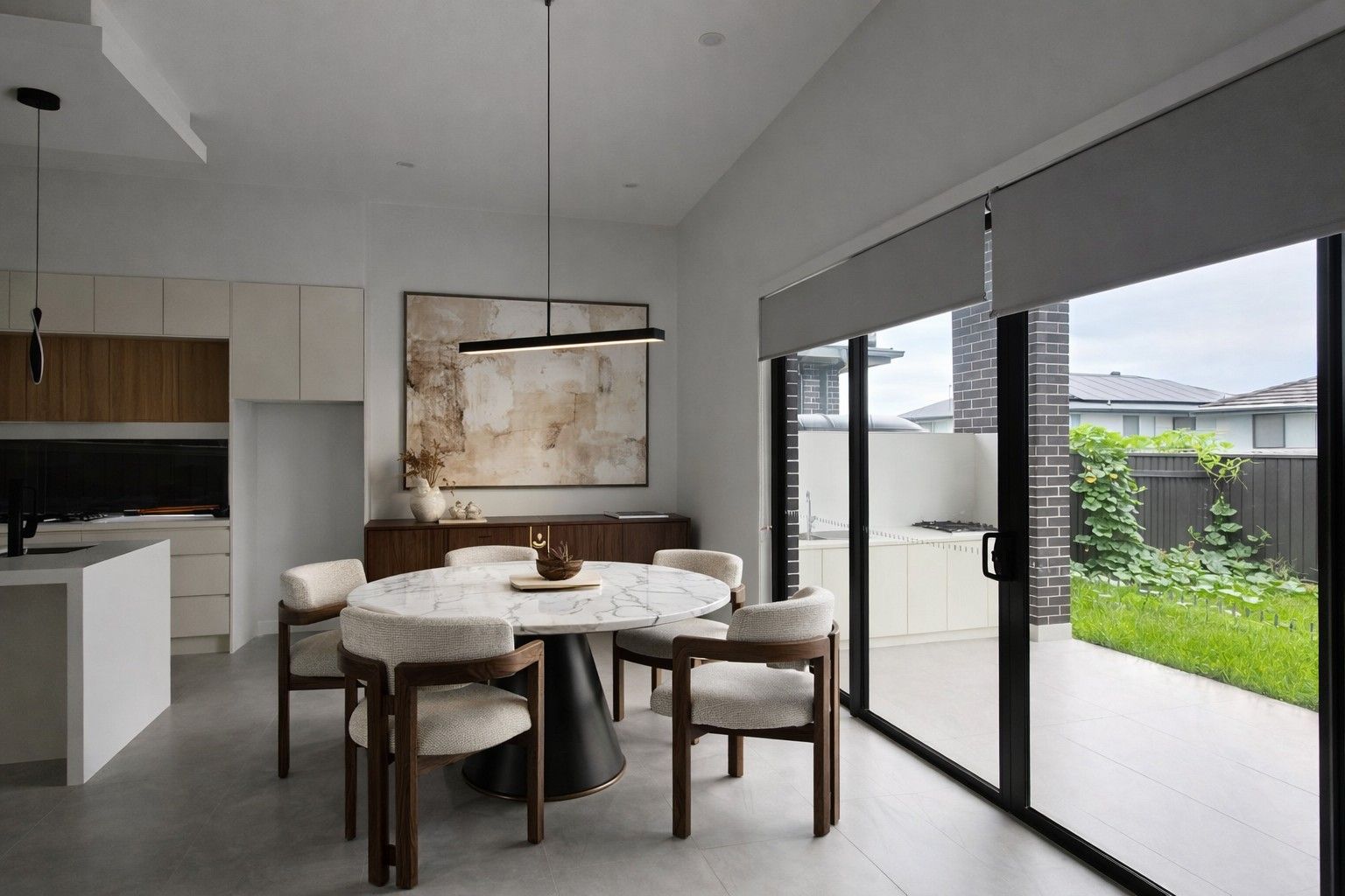 The vision — round dining table and sculptural pendants beside the island